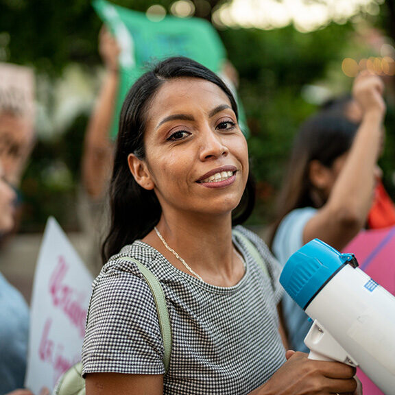 portrait of young woman with a megaphone on a protest outdoors portrait of young woman with a megaphone on a protest outdoors